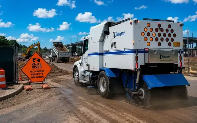 Rear view of a Mid-State sweeper clearing a muddy construction roadway beside a Knife River sign.
